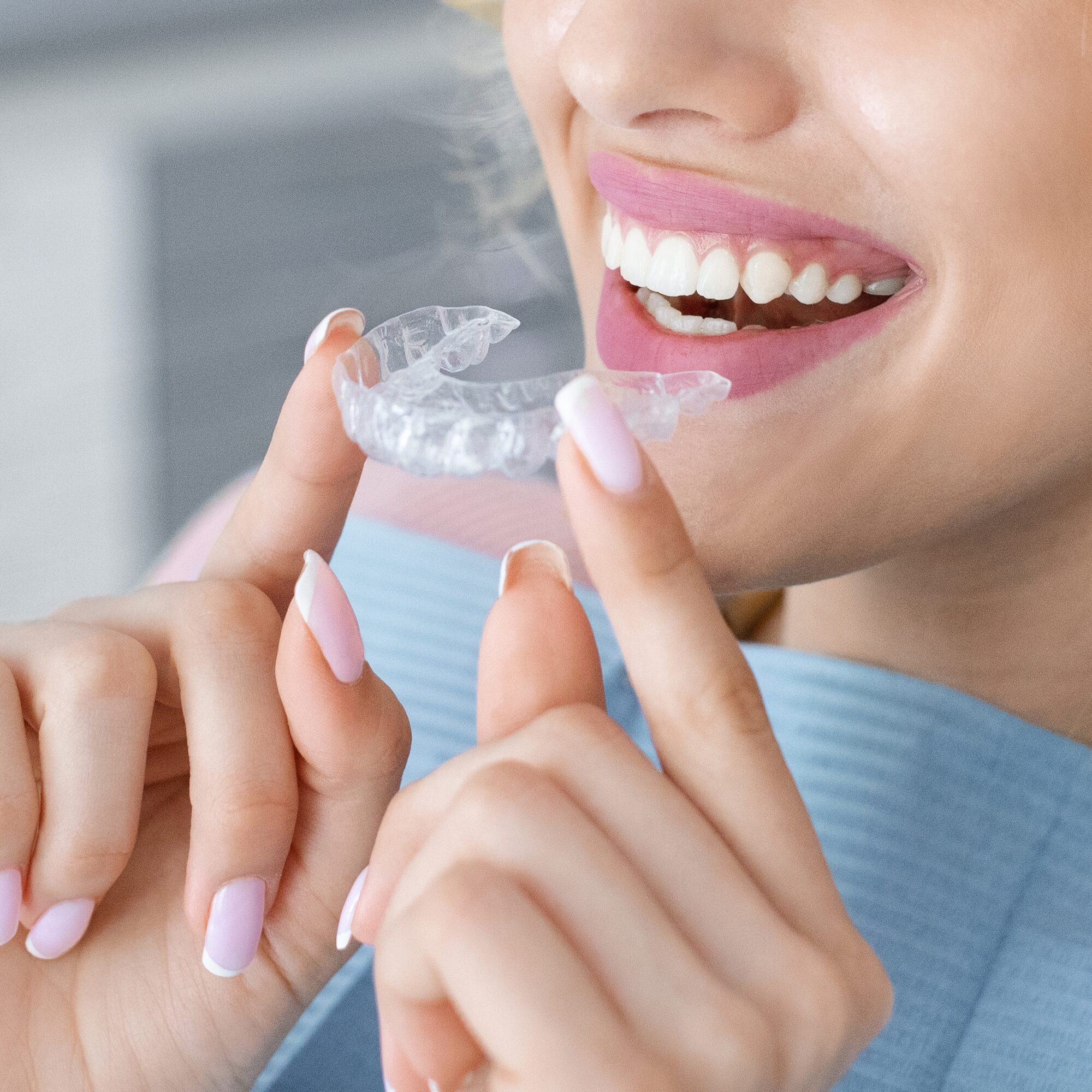 closeup of a young woman putting in her Invisalign clear aligners
