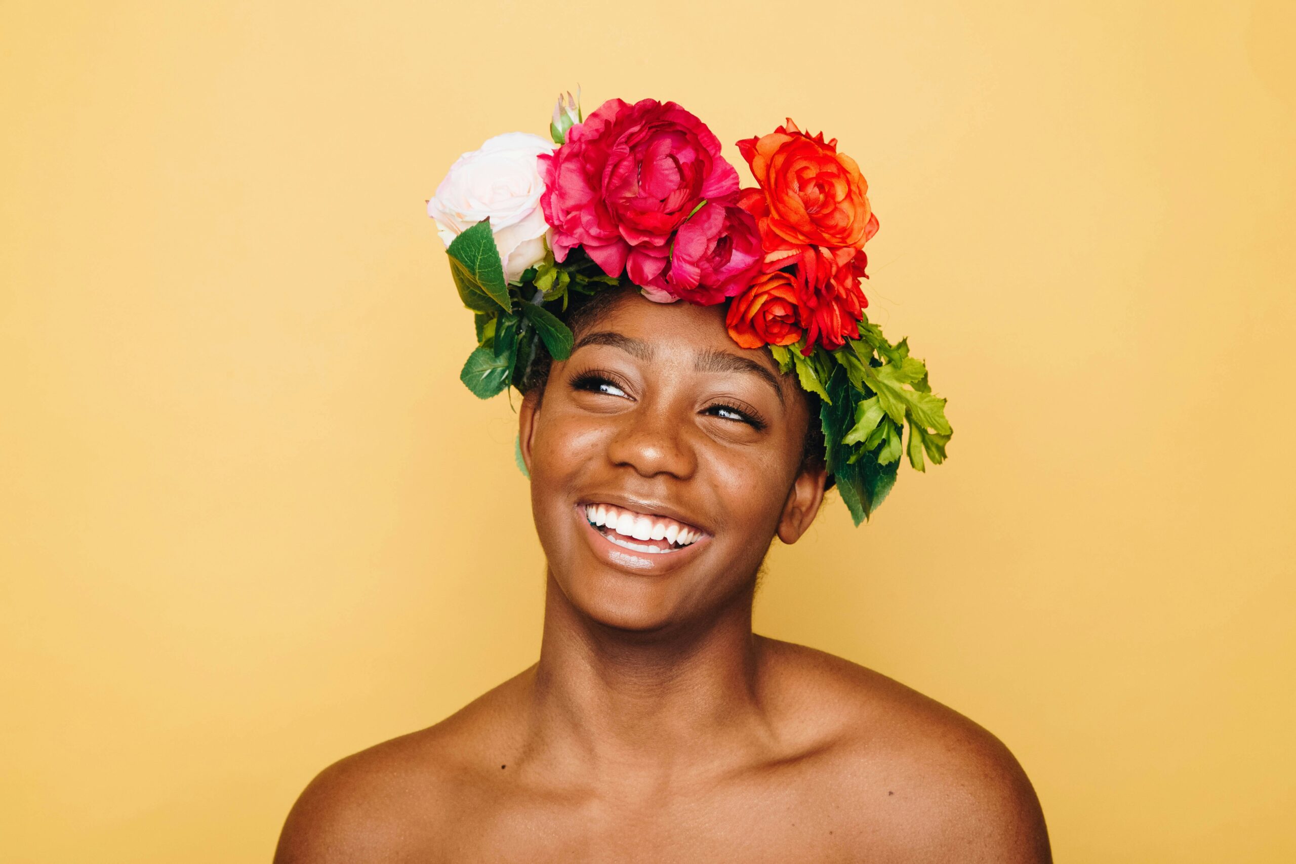 Image of a beautiful woman showing off her beautiful white teeth against a yellow backdrop